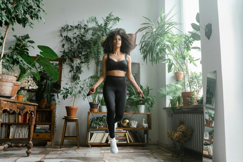 African American woman jumping rope in a plant-filled room, promoting a healthy lifestyle.